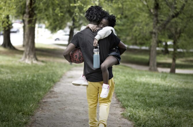 Father walking away from the camera holding daughter