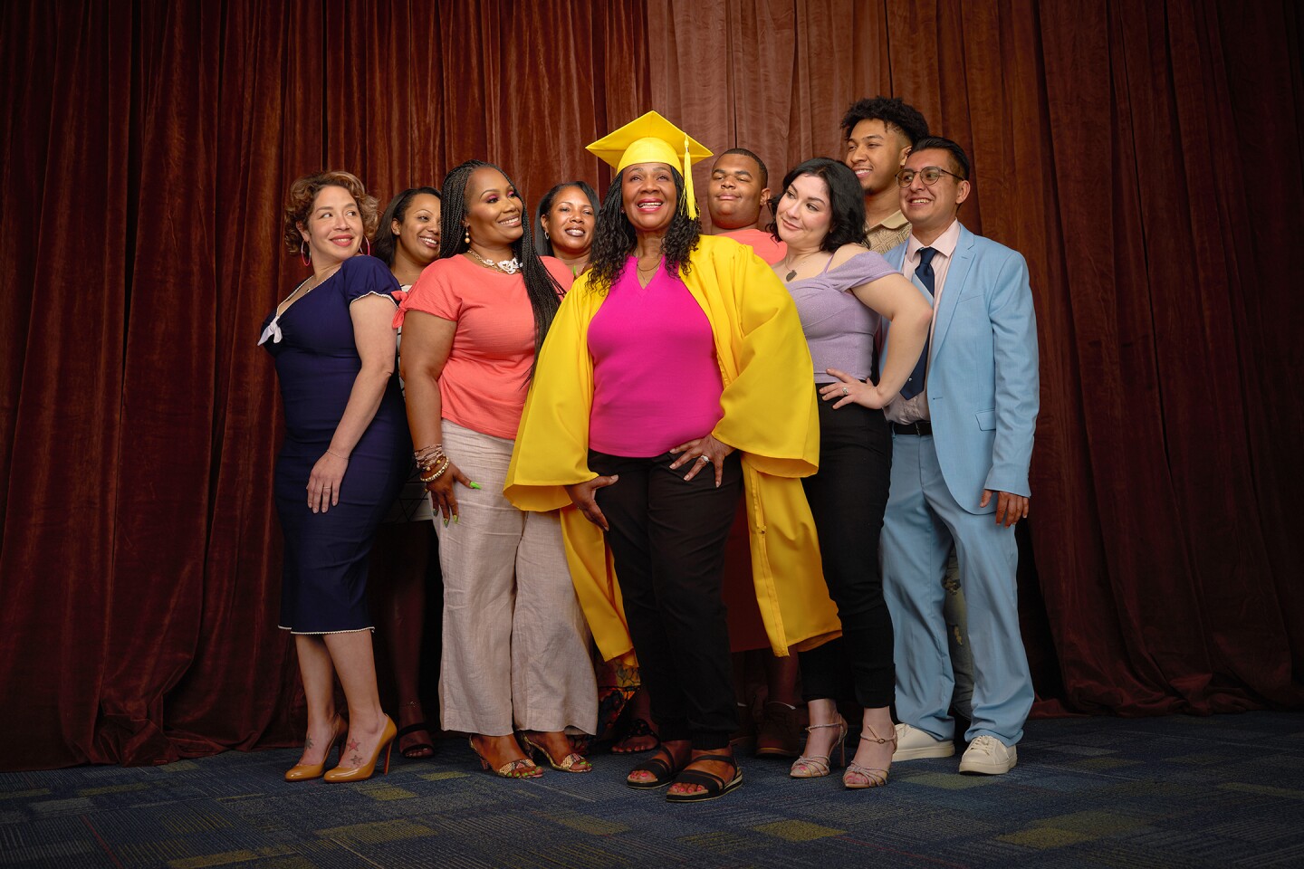 9 people with the center person wearing a graduation gown.