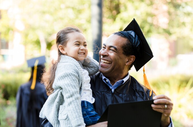 Little girl makes graduating grandfather laugh with silly face